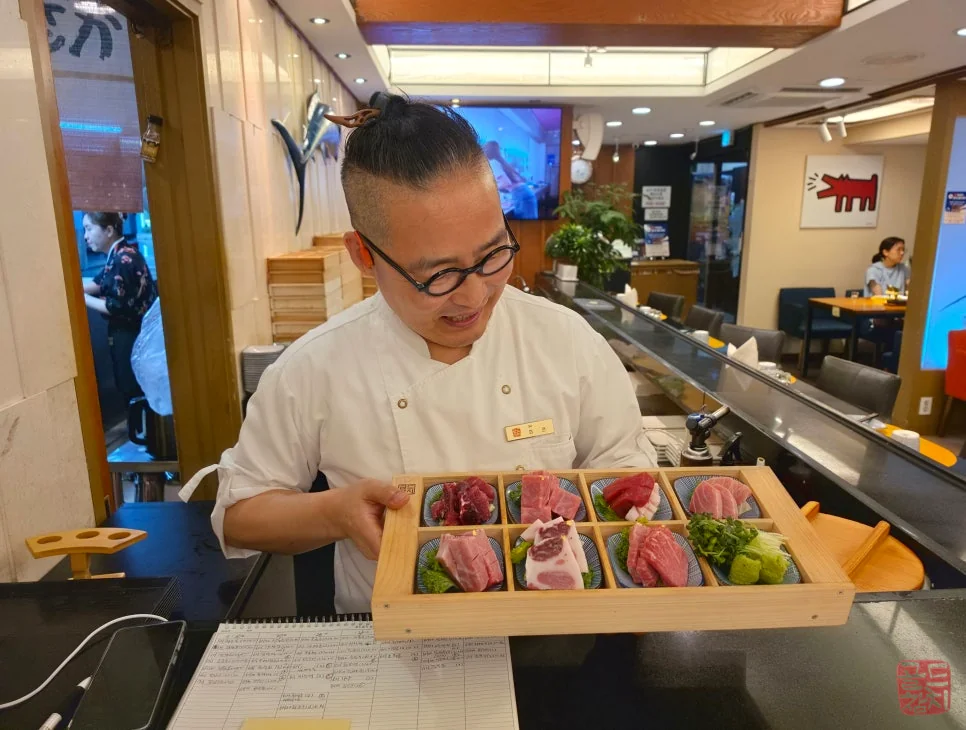 Staff smiling while serving tuna sashimi at Goldtuna Bangi-dong